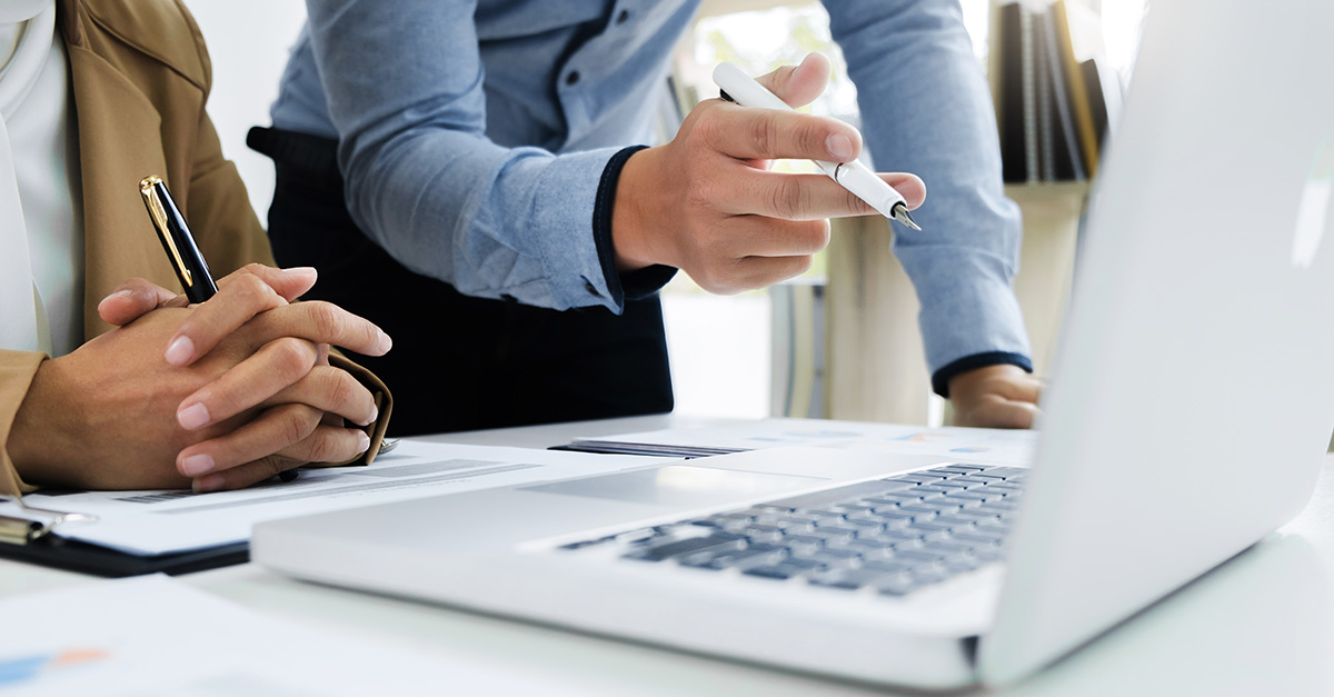 Two business people analysing a finance transaction on a computer screen